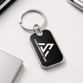Black keychain with a silver ring on a white surface with office supplies.