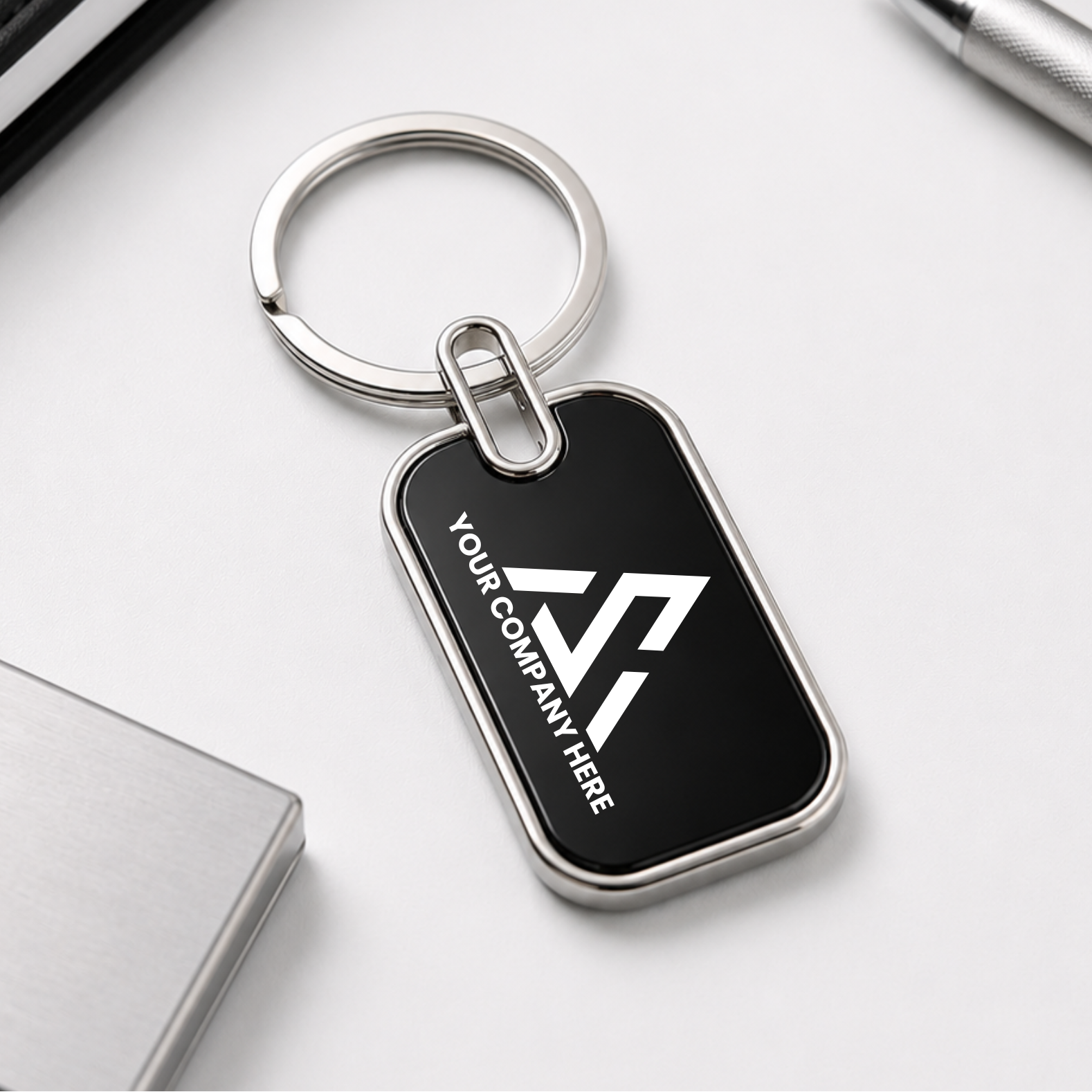Black keychain with a silver ring on a white surface with office supplies.